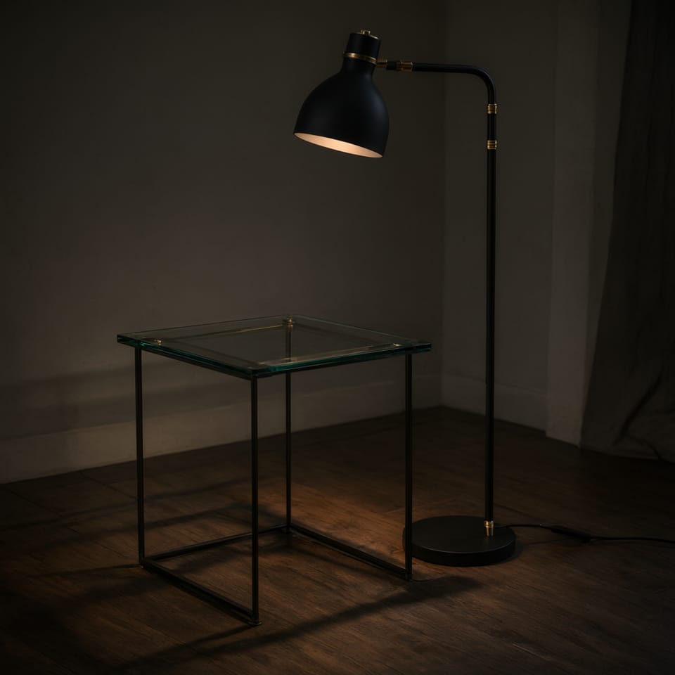 Mesa auxiliar de cristal tintado junto a una lámpara de pie negra proyectando sombras alargadas en la pared